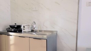 A modern kitchen with a stainless steel sink, a coffee maker, and a stove. - Boten YouJia Residential Hotel (Nateuy)