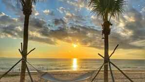 A hammock between two palm trees on a beach at sunset. - The Arenam Cam Ranh Nha Trang Resort (Cam Ranh)