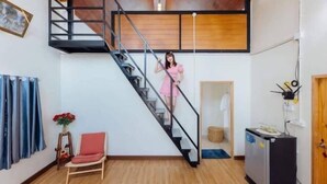 Un intérieur moderne avec un escalier en bois, un petit coin salon et une cuisine compacte.