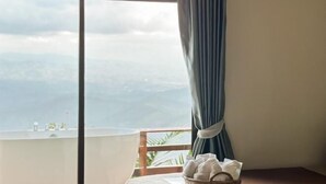 Une chambre avec vue sur les montagnes, une fenêtre avec des rideaux et une table avec des serviettes.