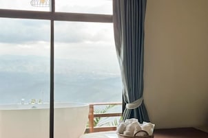 Une chambre avec vue sur les montagnes, une fenêtre avec des rideaux et une table avec des serviettes.