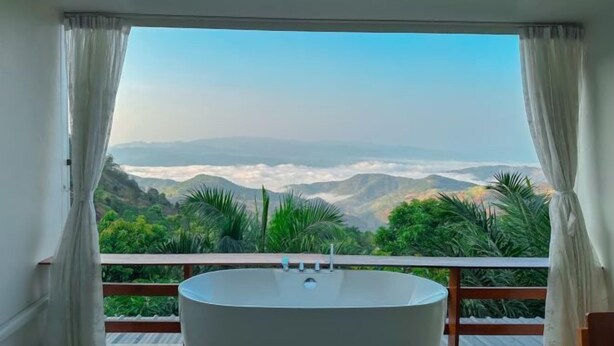 Une salle de bain moderne avec une baignoire sur pieds, de grandes fenêtres et une vue sur un paysage montagneux.