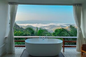 Une salle de bain moderne avec une baignoire sur pieds, de grandes fenêtres et une vue sur un paysage montagneux.