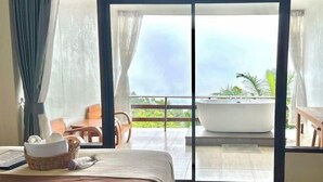 Une chambre dotée d’une grande porte-fenêtre coulissante donnant sur un balcon avec un jacuzzi.