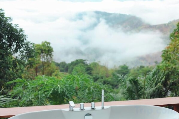 Un lavamanos con vistas a un paisaje montañoso y vegetación.
