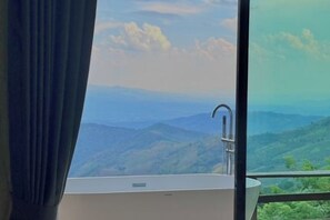 A bathroom with a bathtub, a window with a view of a mountainous landscape, and a curtain. - Masora Doichang (Mae Suai)