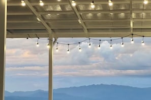 Un espace extérieur abrité, décoré de guirlandes lumineuses, et offrant une vue sur les montagnes.