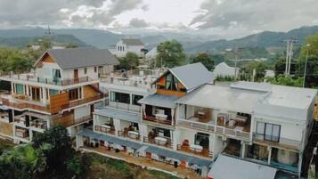 Un edificio residencial de varios pisos con balcones, techo plano y vistas del paisaje circundante.