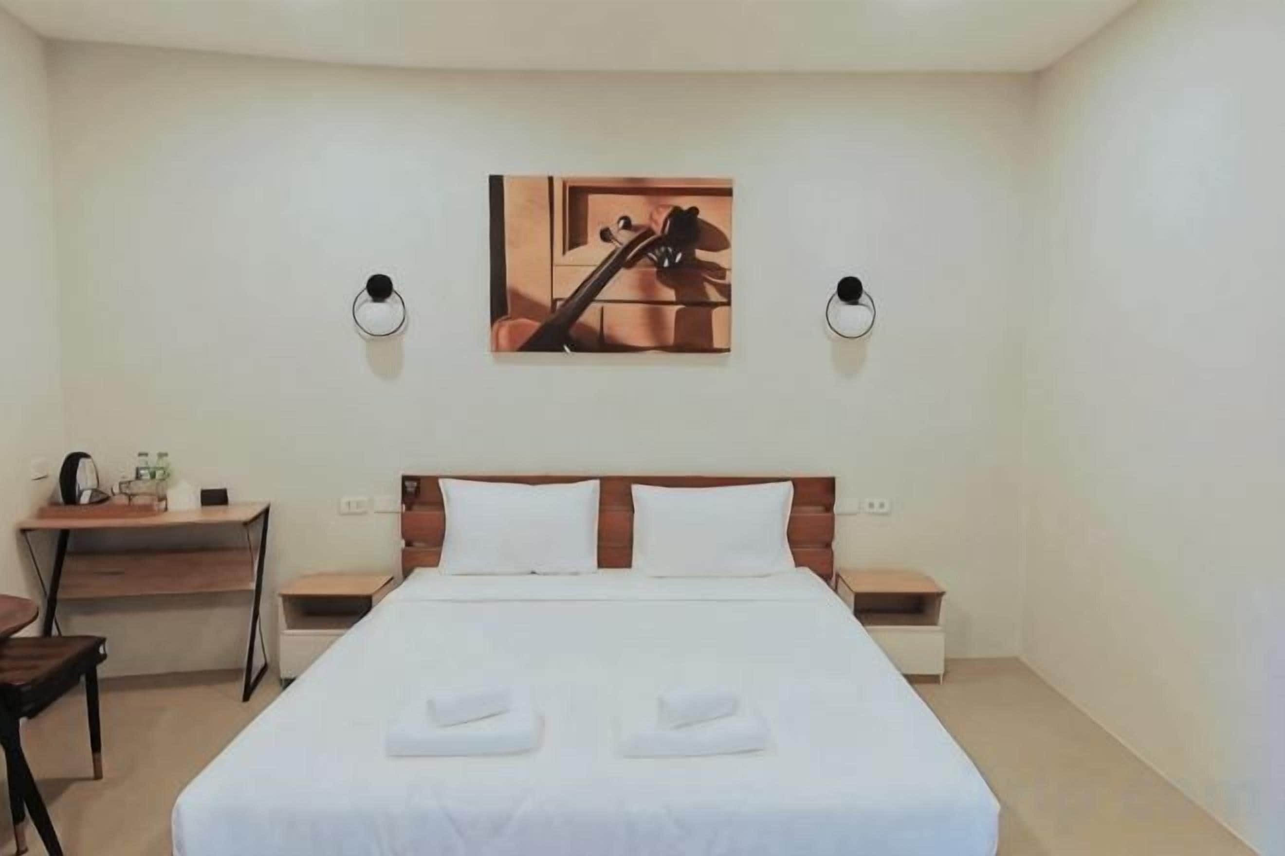 Una habitación de hotel con cama, escritorio y silla.