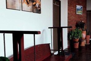 A hallway with a wooden bench, a potted plant, and a door. - Studio251 HOUSE (Lang Suan)