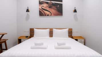 A neatly made bed with white linens and two towels, a wooden headboard, bedside tables with lamps, and a wall-mounted artwork.
