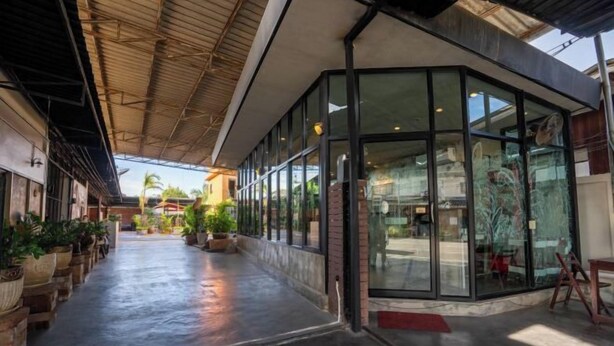 A covered walkway with potted plants, large windows, and a modern architectural design. - Studio251 HOUSE (Lang Suan)