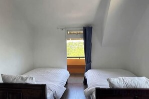 A room with two single beds, a window with a view of greenery, and a curtain. - Michelia Valley Hotel (Dalat)
