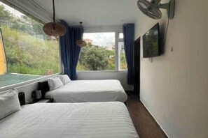 A room with two beds, a television, and a window with curtains. - Michelia Valley Hotel (Dalat)