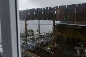 Blick auf einen Raum mit einem Holzzaun davor, einem Fenster und dem Spiegelbild eines Gebäudes.
