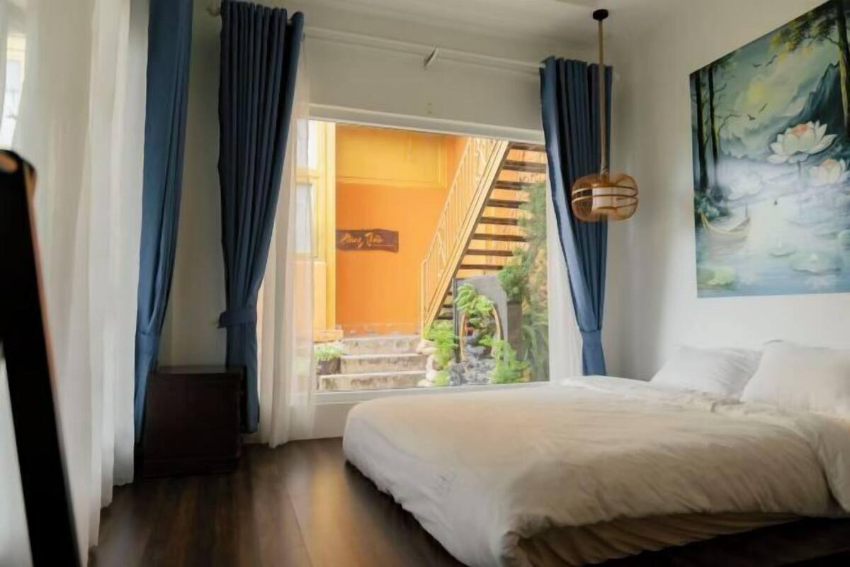 A bedroom with a bed, a staircase leading to an outdoor area, and a painting on the wall.