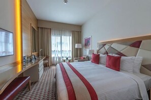 A hotel room with a large bed, a desk, a chair, a TV, and a window with curtains. - Gulf Inn Hotel Al Nasr, Bur Dubai (Dubai)