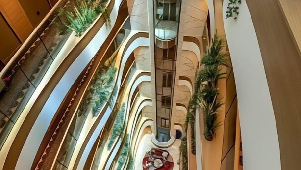 A multi-level atrium with curved balconies, a central elevator, and greenery. - Gulf Inn Hotel Al Nasr, Bur Dubai (Dubai)