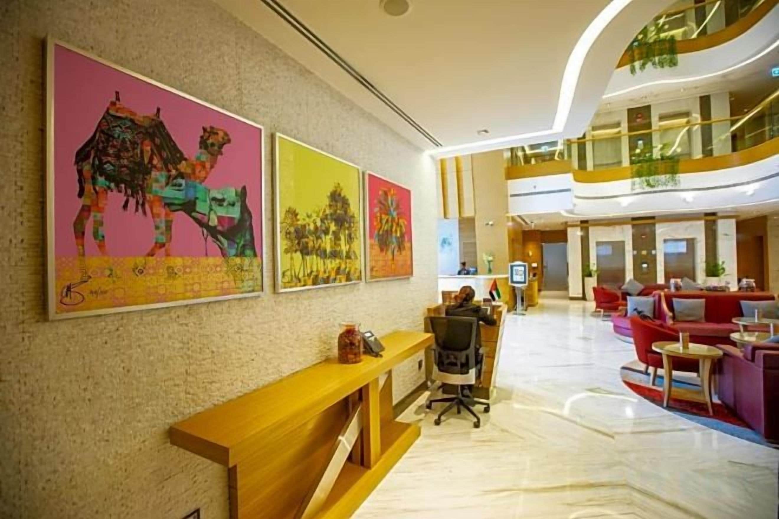 A hotel lobby with a reception desk, seating area, and artwork on the walls.