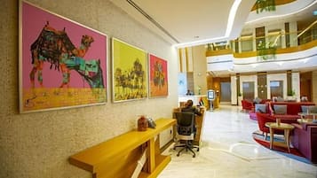 A hotel lobby with a reception desk, seating area, and artwork on the walls.