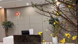 A reception desk with a logo, a potted plant, and a wall with a sign. - Vinhone Grand Park Homestay - ZEN Garden Residence (Ho Chi Minh City)