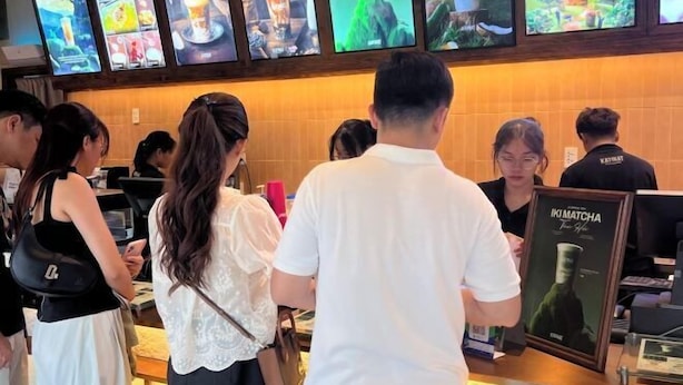 A restaurant interior with a counter, menu boards, and staff uniforms. - Vinhone Grand Park Homestay - ZEN Garden Residence (Ho Chi Minh City)