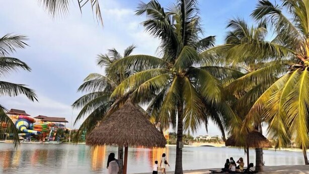 Ein Strand mit Palmen, einer Wasserrutsche und einer Hütte mit Reetdach.