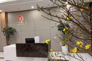 A reception desk with a logo, a plant, and a wall-mounted sign.