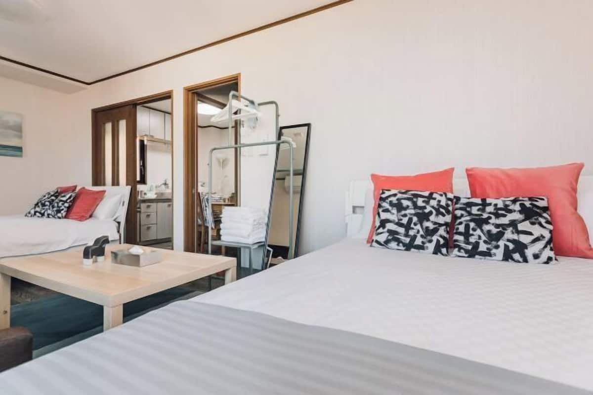 A hotel room with two beds, a small table, a mirror, and a desk with a chair.