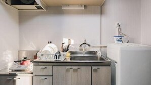 A compact kitchen with a sink, countertop, and a built-in dishwasher. - Nippombashi Back Kuromon AFP Apartment (Osaka)