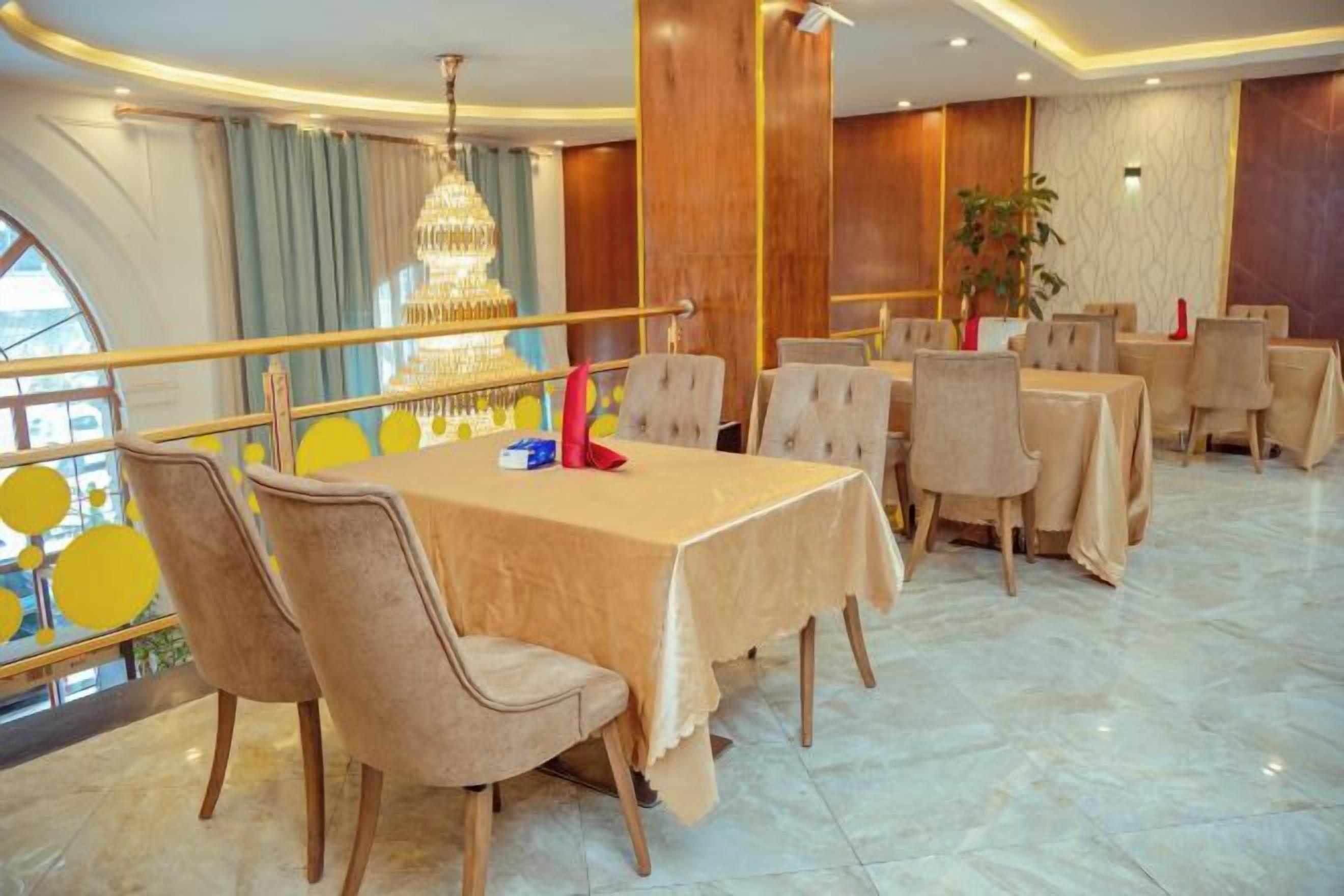 A dining area with round tables, chairs, and a chandelier.