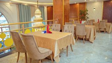 A dining area with round tables, chairs, and a chandelier.