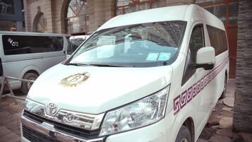 A white van with a logo on the front, parked in front of a building with arched windows.