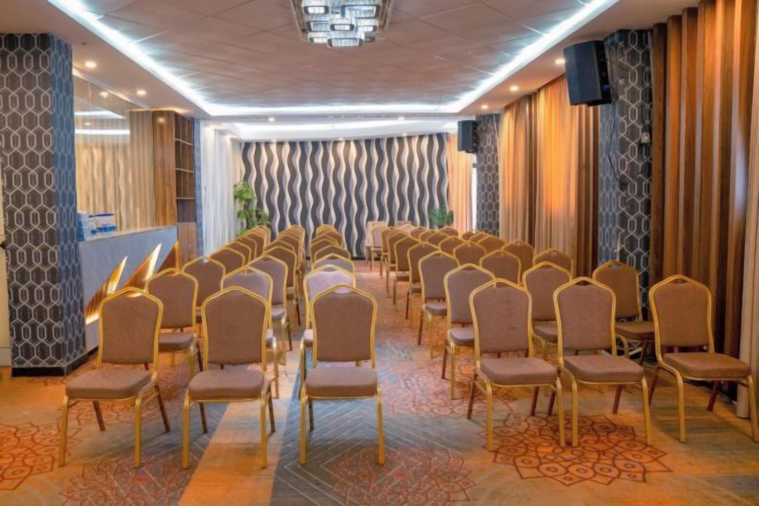 A conference room with rows of chairs, a reception desk, and a patterned wall.