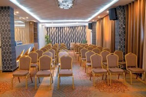 A conference room with rows of chairs, a reception desk, and a patterned wall. - BOYUE Hotel (Addis Ababa)