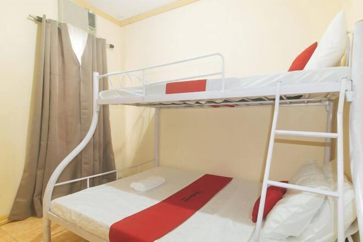 A bunk bed with a red bed runner and white bedding.