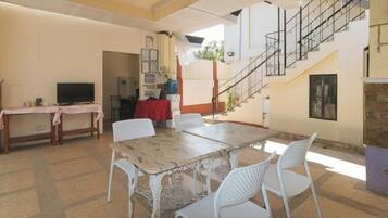 A dining area with a table and chairs, a television, and a staircase leading to an upper level.