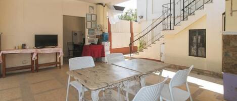 A dining area with a table and chairs, a television, and a staircase leading to an upper level.