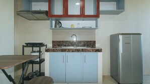 A compact kitchen with a sink, cabinets, a stove, and a refrigerator. - RedDoorz @ Yssa Ademar near Robinsons Jaro (Iloilo City)