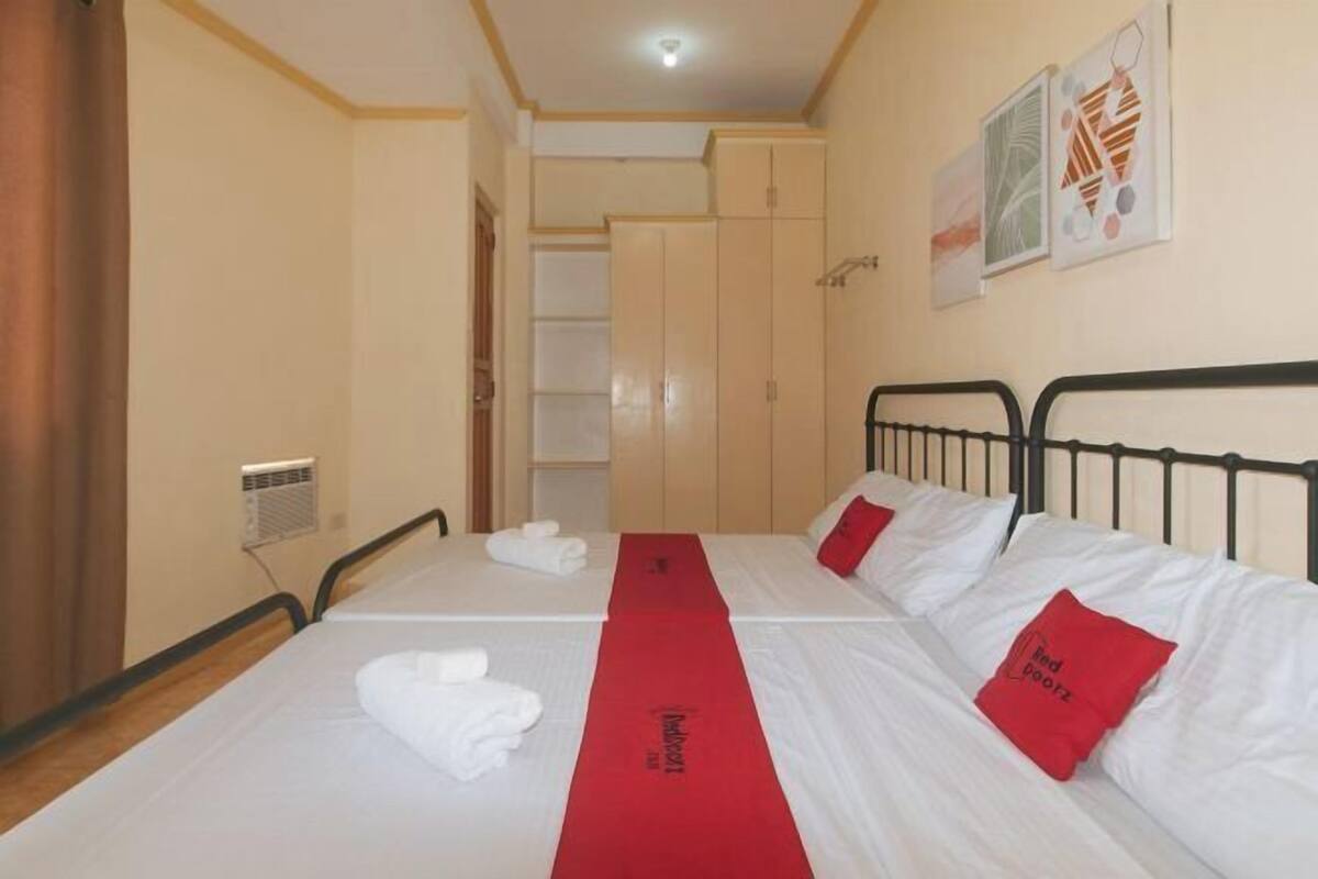 A hotel room with two beds, a red towel on the floor, and a door to a bathroom.
