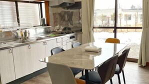 Une cuisine moderne dotée d’un grand îlot central, d’appareils électroménagers en acier inoxydable et offrant une vue sur l’extérieur.