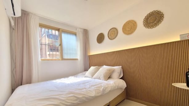 A bedroom with a bed, a window with curtains, and a wall with decorative plates.