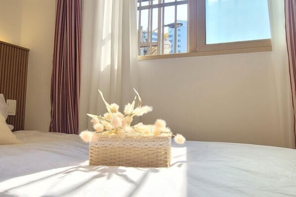 A hotel room with a bed, a wicker basket with dried flowers, and a window with a view of buildings. - Airport Railroad Gongdeok Station 800m/3 Rooms/6 people/3 Queen Beds/Dryer/Hongik University (Seoul)