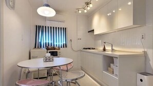 A modern kitchen with white cabinets, a round dining table with metal chairs, and pendant lighting.