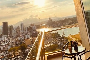 A balcony with a glass railing overlooking a cityscape, including buildings and a river. - Kuching City Center Riverine Apartment With Balcony & City Views (Kuching)