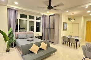 A modern bedroom with a bed, sofa, dining table, chairs, and a ceiling fan. - Kuching City Center Riverine Apartment With Balcony & City Views (Kuching)