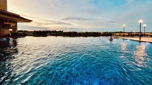 A swimming pool with clear water, surrounded by a building and a view of the horizon. - Kuching City Center Riverine Apartment With Balcony & City Views (Kuching)