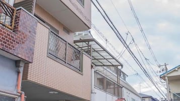 A residential building with multiple balconies, a brick facade, and a clear sky.