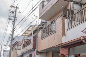 Un edificio residencial de varios pisos con balcones, cableado eléctrico a la vista y fachada de ladrillo.