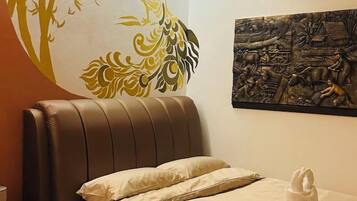 A hotel room with a brown leather headboard, a bed with beige bedding, a wall mural, and a towel sculpture on the bed.